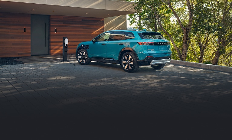 2026 Honda Prologue Elite in North Shore Pearl back charging at a home station in a driveway (All-Electric SUV). 2026 Honda Prologue Elite in North Shore Pearl back charging at a home station in a driveway (All-Electric SUV).